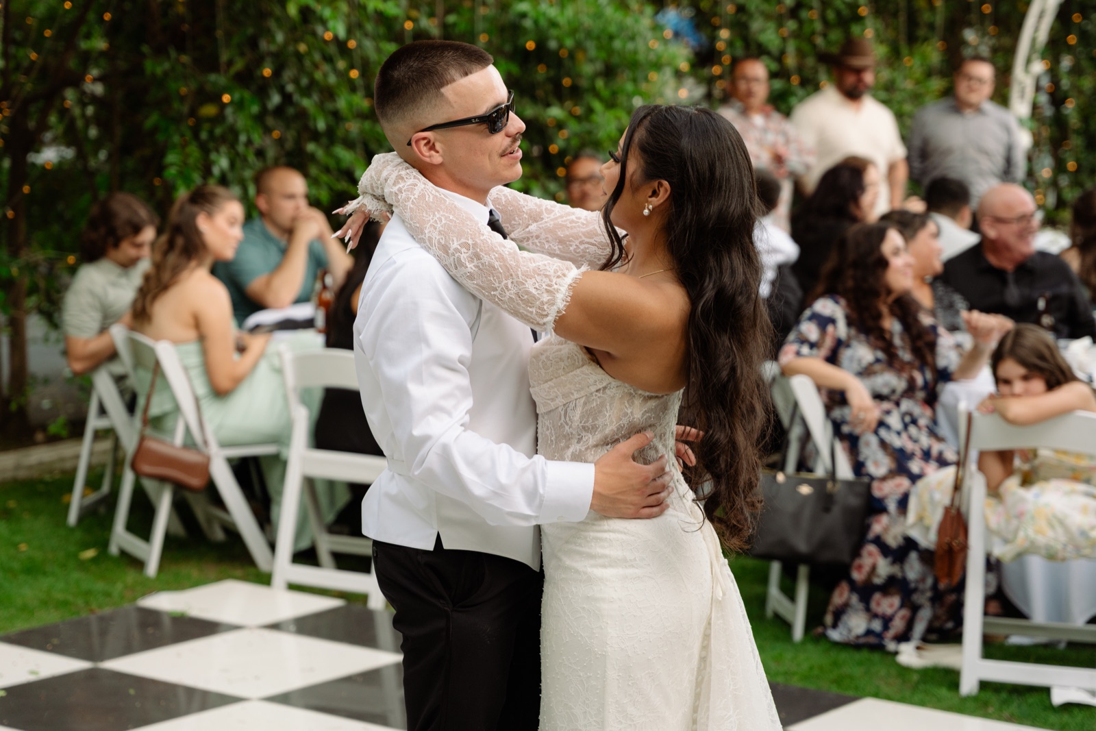 Bride and groom dancing together surrounded by wedding guests