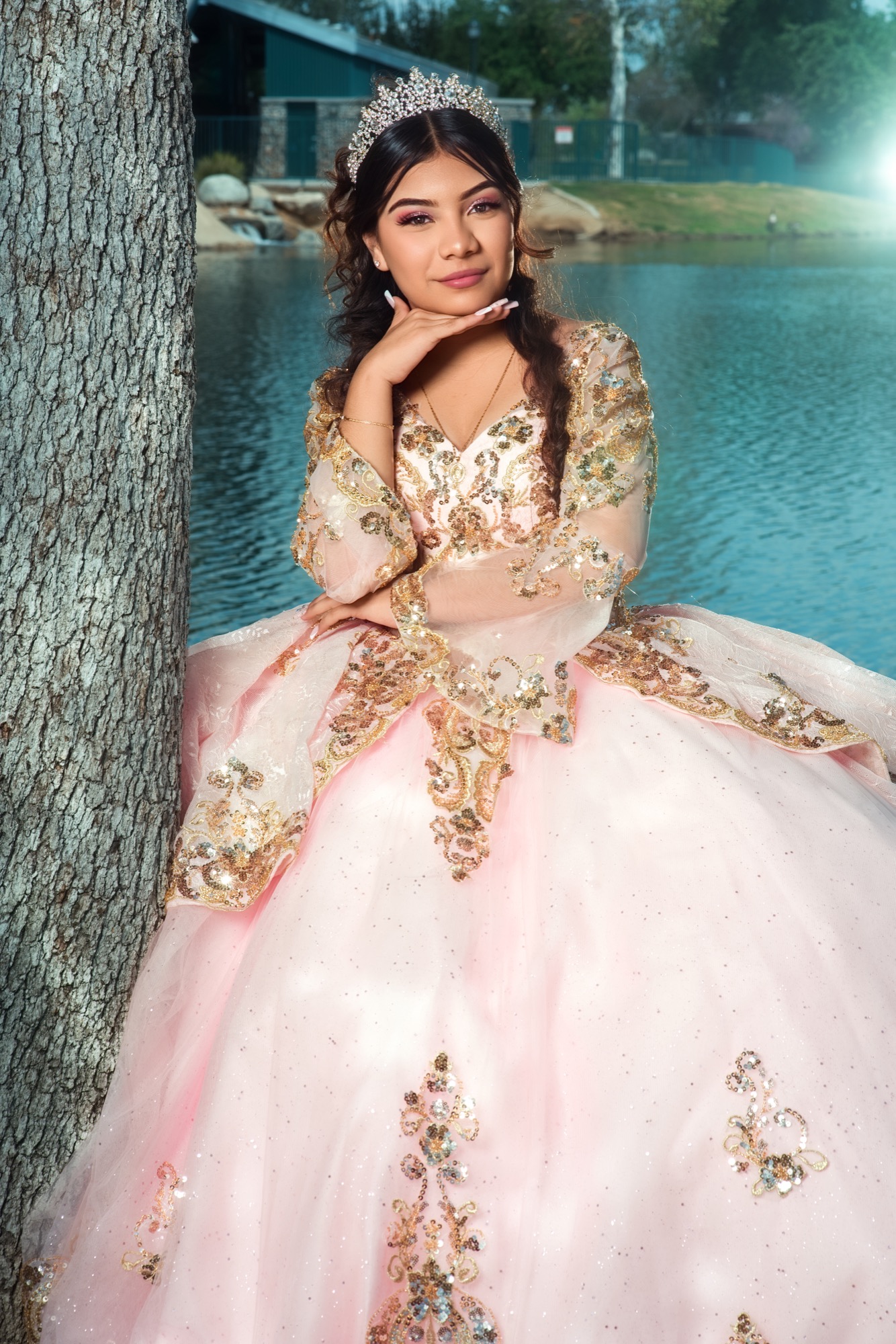 Quinceañera portrait in a pink dress beside the lake